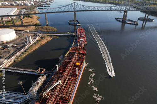 A boat passes under the Outerbridge Crossing and past chemical tankers unloading in Perth Amboy, NJ photo