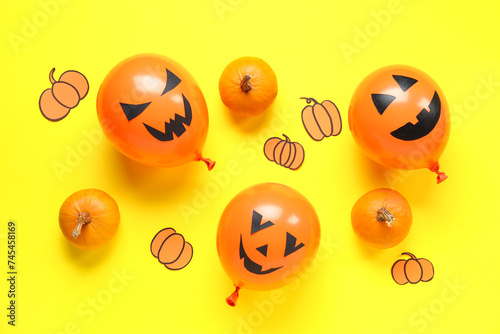 Funny Halloween orange balloons and paper pumpkins on yellow background