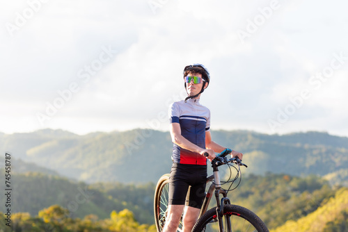 Fototapeta Naklejka Na Ścianę i Meble -  Brazilian cyclist resting beside his mountain bike atop a mountain, enjoying nature's tranquility. The image portrays the cyclist lifestyle and mountain biking enthusiasts	