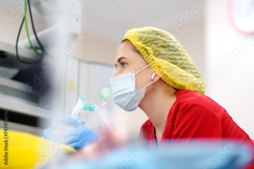 Female anesthesiologist injects anesthesia into patient face mask. General sedation while surgery operation. Paramedic putting oxygen mask for breathing and ventilation of person during resuscitation photo