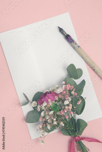 Bukiecik subtelnych kwiatków na kartce papieru i pióro do kaligrafii. 