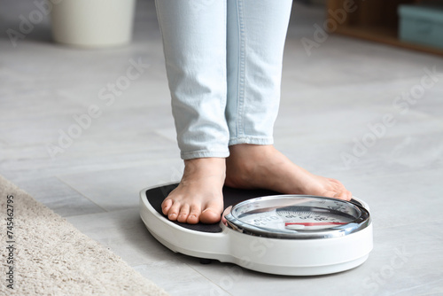 Obraz na plátně Young woman standing on scales at home. Weight loss concept