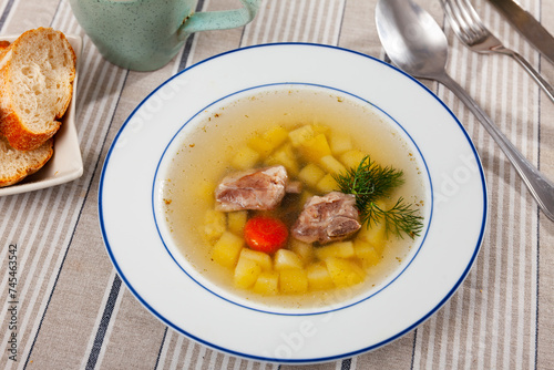 Appetizing soup in pork broth with potatoes, carrots and onions seasoned with herbs. Comfort food .