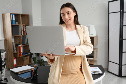Young businesswoman using laptop computer in modern office, professional remo...