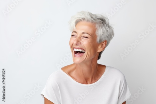 Portrait of a happy senior woman laughing against a white background.