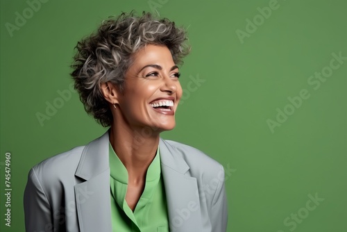 Portrait of a smiling middle-aged businesswoman in a suit on a green background