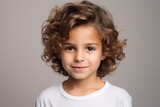 Portrait of a cute little girl with curly hair over grey background