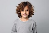 Portrait of a cute little boy with curly hair, over grey background