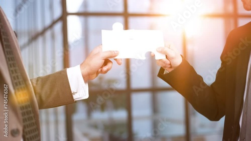 Close-up Of Business Partners Combining Two White Puzzle Pieces photo