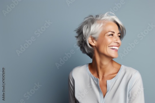 Portrait of a happy senior woman with grey hair, over grey background