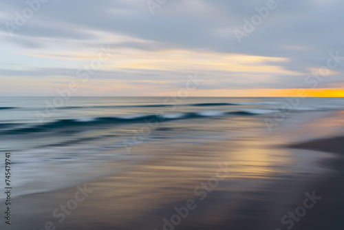 Last rays of the sunset cast a vibrant glow over the blurred motion of ocean waves