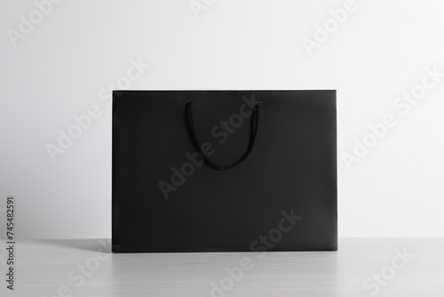 Black paper bag on white wooden table