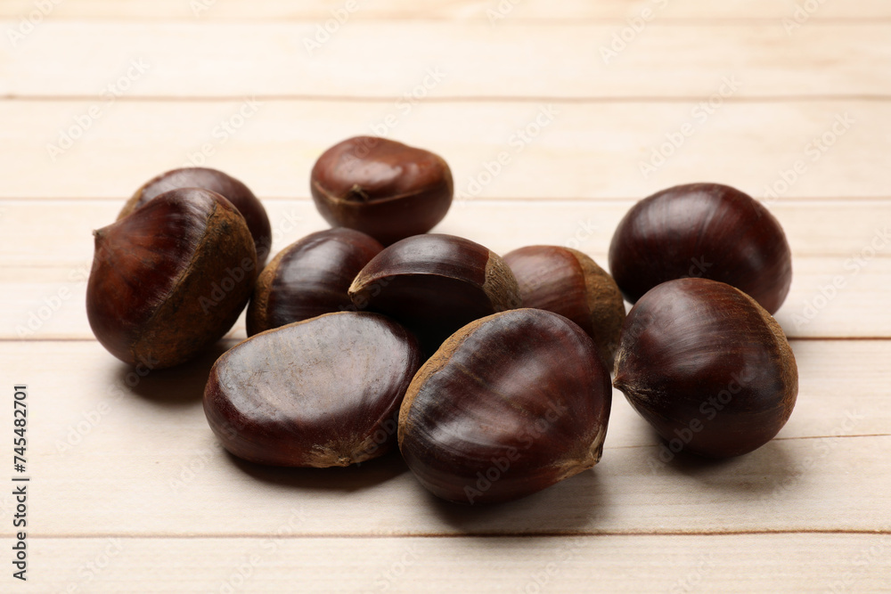 Sweet fresh edible chestnuts on light wooden table, closeup Sweet fresh edible chestnuts on light wooden table, closeup