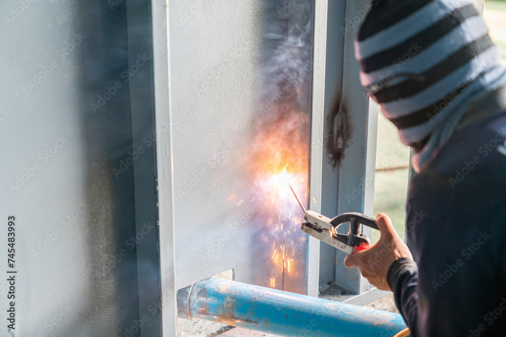 Obraz premium A metal welder welds metal a wall in a warehouse.
