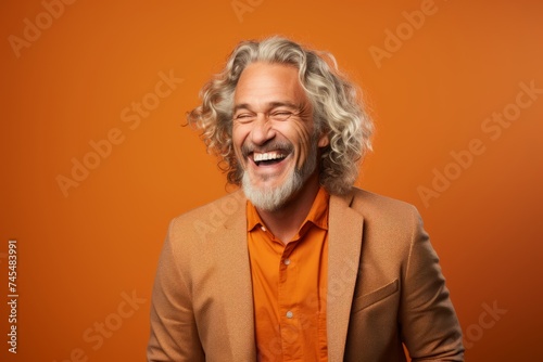 happy senior man laughing and looking at camera on orange background, empty space © Inigo