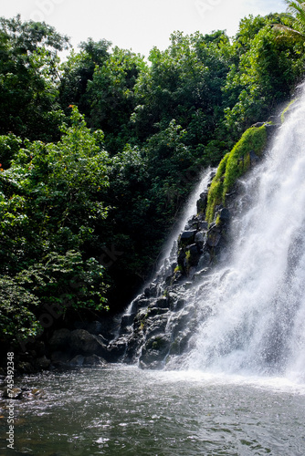 Scenic view of Kepirohi Waterfall with free flowing white water cascading over rocks surrounded by jungle on the tropical island of Pohnpei in Federated States of Micronesia