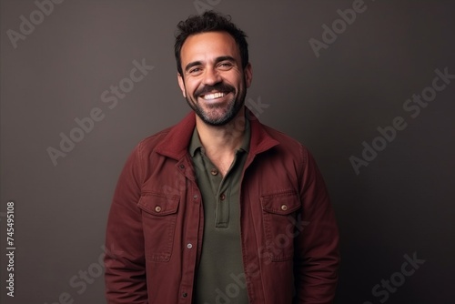 Portrait of a happy casual man smiling at the camera on a dark background © Inigo