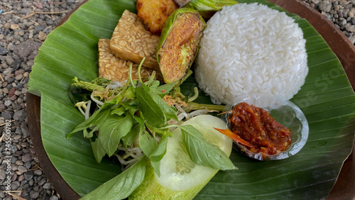 Tempong) with sambal or traditional sauce from Indonesia, Fried fermented soybean cakes, Tomato, cucumber, Cabbage, and basil leaves