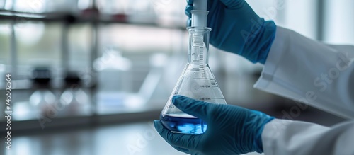 Scientist hand with gloves holding conical flask lab glassware on chemical laboratory background