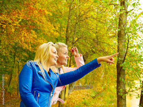 Two women walking in autumn park photo