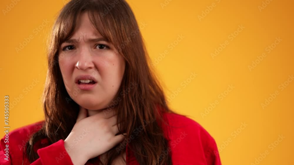 Portrait of young woman wearing red jacket 20s sick with cough and sore throat isolated on yellow background in studio with copy space in slow motion Portrait of young woman wearing red jacket 20s sick with cough and sore throat isolated on yellow background in studio with copy space in slow motion