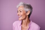 Portrait of a happy senior woman smiling against purple background. Copy space
