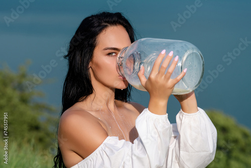Portrait of sexy model with bottle of milk. Female mouth with dripping milking. Pretty woman drinking milk. Young woman in lingerie drinking milk. Model drink Milk at Alpine meadow. Milky face.