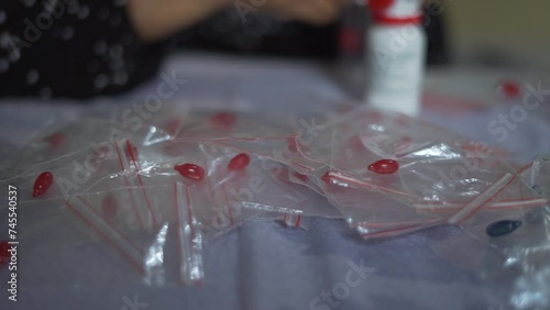 Nurse hands put Vitamin A supplement capsule in to plastic packaging. Close up selective focus photo