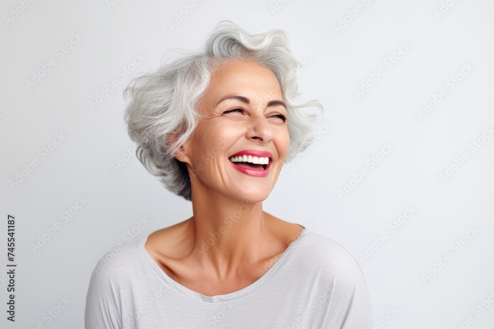 Portrait of a happy senior woman laughing and looking up against grey background Portrait of a happy senior woman laughing and looking up against grey background