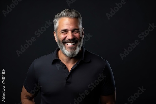 Handsome middle age man with gray beard and mustache smiling on black background