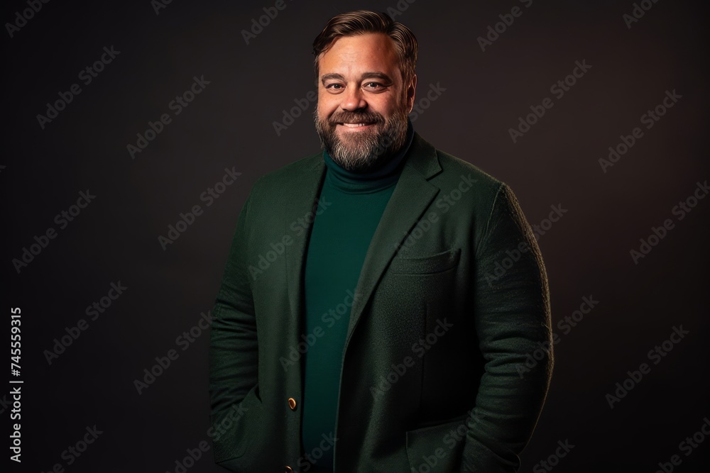 Handsome middle age man with beard and mustache wearing green coat on dark background
