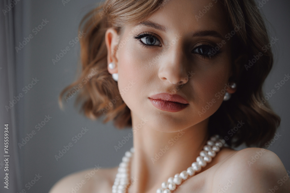 Portrait of happy elegant young woman in modern bridal look with classic hairstyle and makeup with pearl necklace Portrait of happy elegant young woman in modern bridal look with classic hairstyle and makeup with pearl necklace