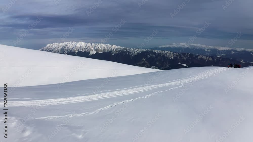 Snowy mountain ridge with Piatra Craiului in the distance, Iezer-Papusa, Arges, Romania, under a clear sky Snowy mountain ridge with Piatra Craiului in the distance, Iezer-Papusa, Arges, Romania, under a clear sky