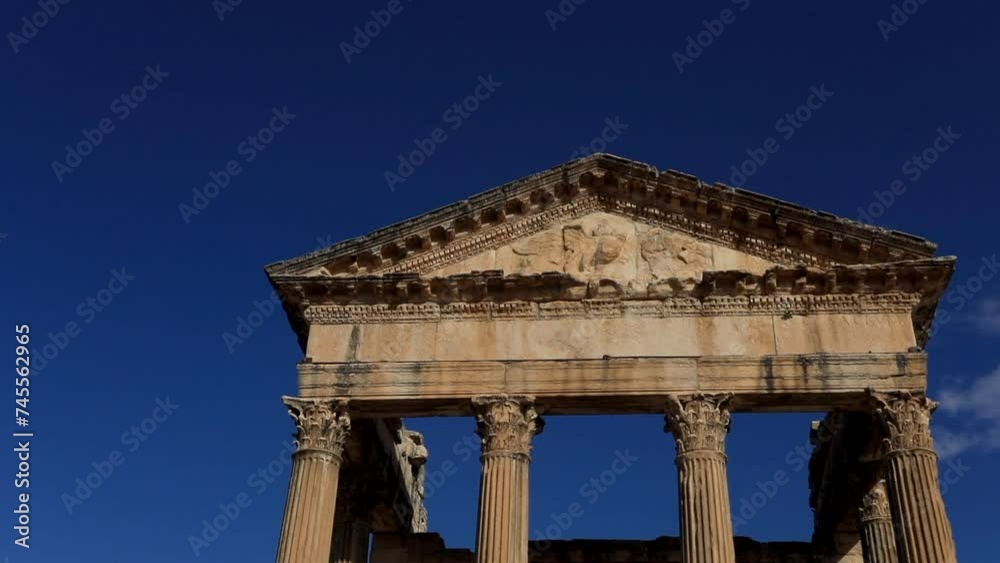 Sunlit ancient Roman ruins at Dougga against a clear blue sky, highlighting historical architecture Sunlit ancient Roman ruins at Dougga against a clear blue sky, highlighting historical architecture