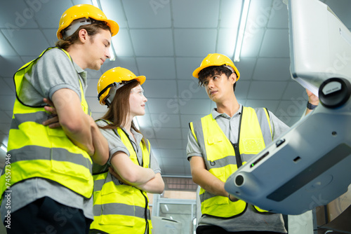 Both of  young factory worker wearing a hard hat looking at a computer screen used to control production.