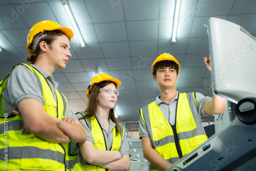 Both of young factory worker wearing a hard hat looking at a computer screen used to control production.