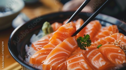 The hands were holding the chopsticks to hold the salmon sashimi
