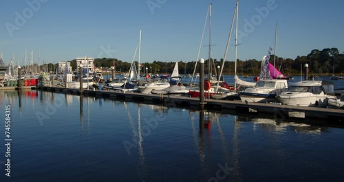 speed up shot of multiple sailing dinghies sailing past moored up motor yachts and out of frame on Lymington river photo