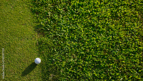 Golf ball on green grass in the evening golf course with sunshine background. Golf ball on the edge of hole on the green grass with warm tone and sunset