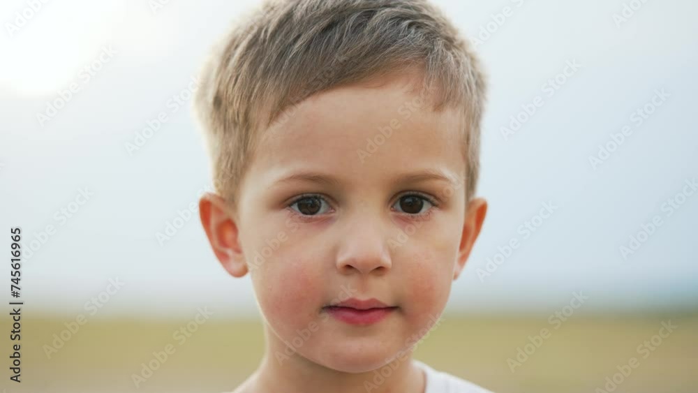 Portrait of a child. Cheerful happy kid boy in summer park at sunset. Dream kid child look into the camera on nature in the park. Toddler child playing outdoors on green grass portrait. Happy child Portrait of a child. Cheerful happy kid boy in summer park at sunset. Dream kid child look into the camera on nature in the park. Toddler child playing outdoors on green grass portrait. Happy child