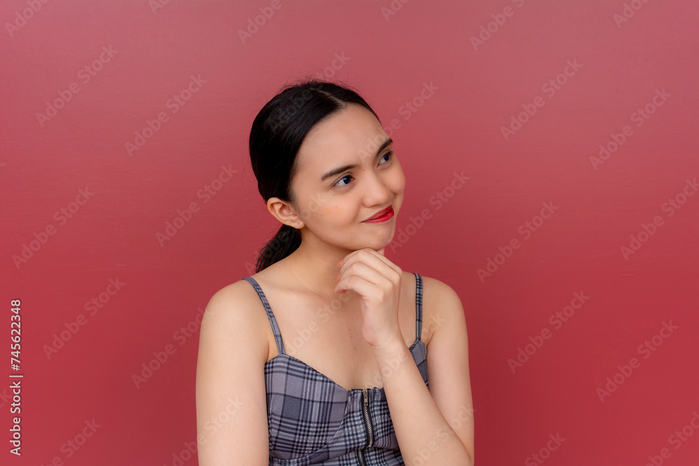 Cheerful young Asian woman smiling thoughtfully. Perfect image to represent positivity and happy thoughts.