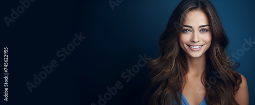 Portrait of a beautiful, sexy happy smiling woman with perfect skin and long hair, on a dark blue background, banner.