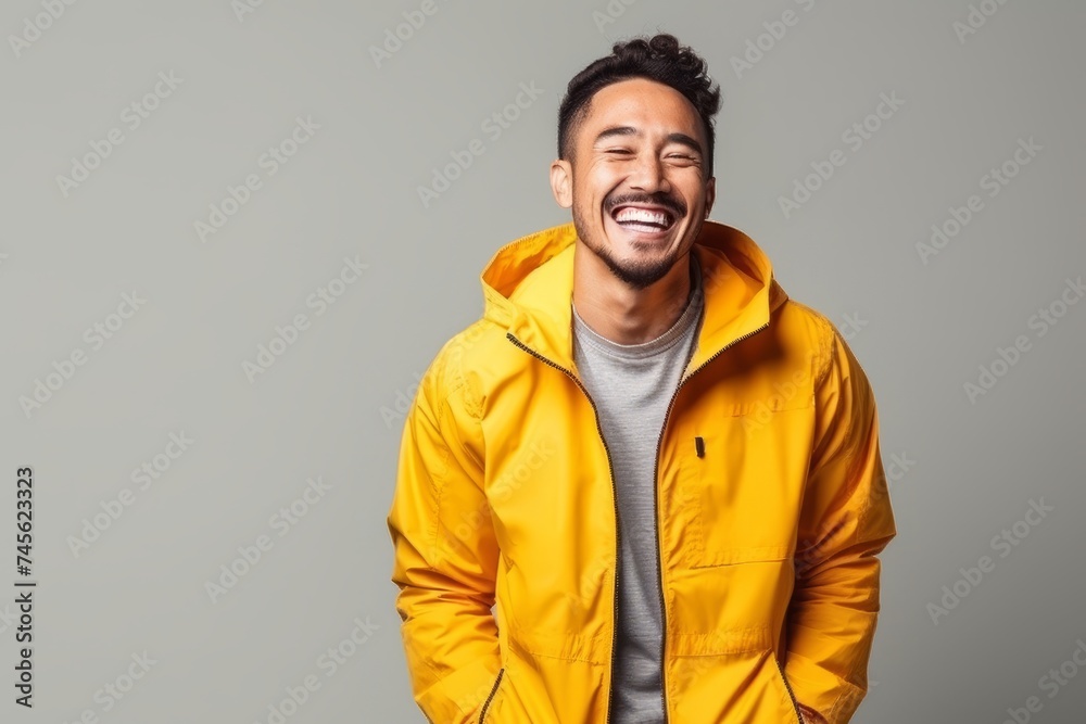 Portrait of a happy young man laughing and looking at camera against grey background Portrait of a happy young man laughing and looking at camera against grey background