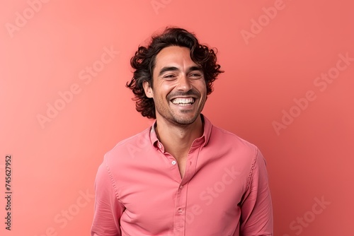Portrait of a handsome young man with curly hair on a pink background