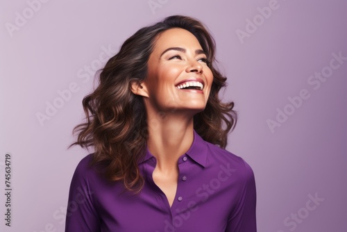 Portrait of happy smiling young woman in purple shirt, over violet background