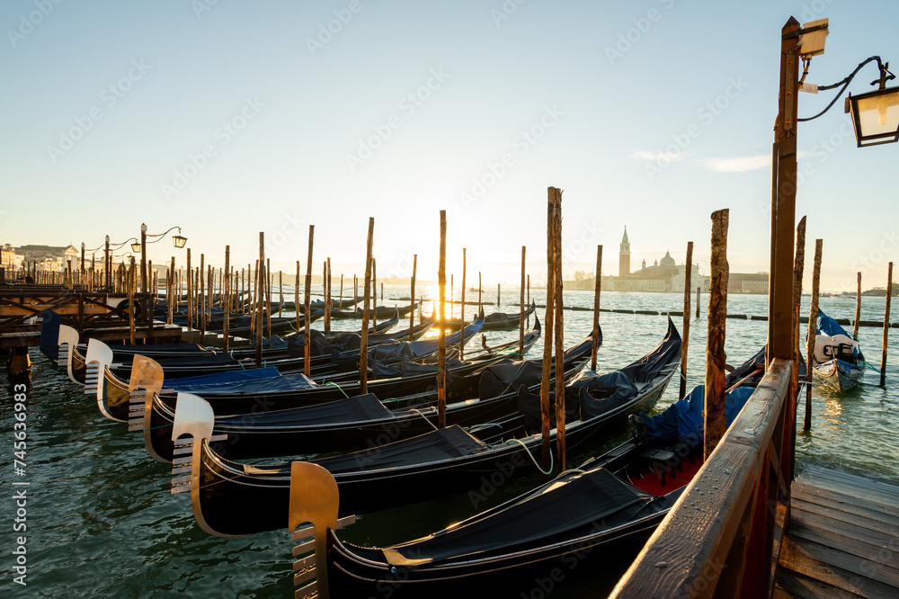 Venedig, Gondeln im Morgenlicht , liegen in der Lagune vor der Insel San Giorgio Maggiore mit dem Kloster des Heiligen Georg.