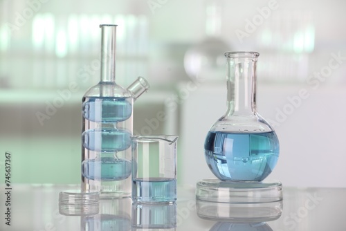 Laboratory analysis. Different glassware with liquid on white table against blurred background