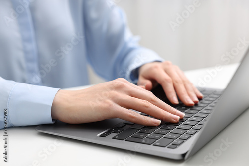 E-learning. Woman using laptop at white table indoors  closeup