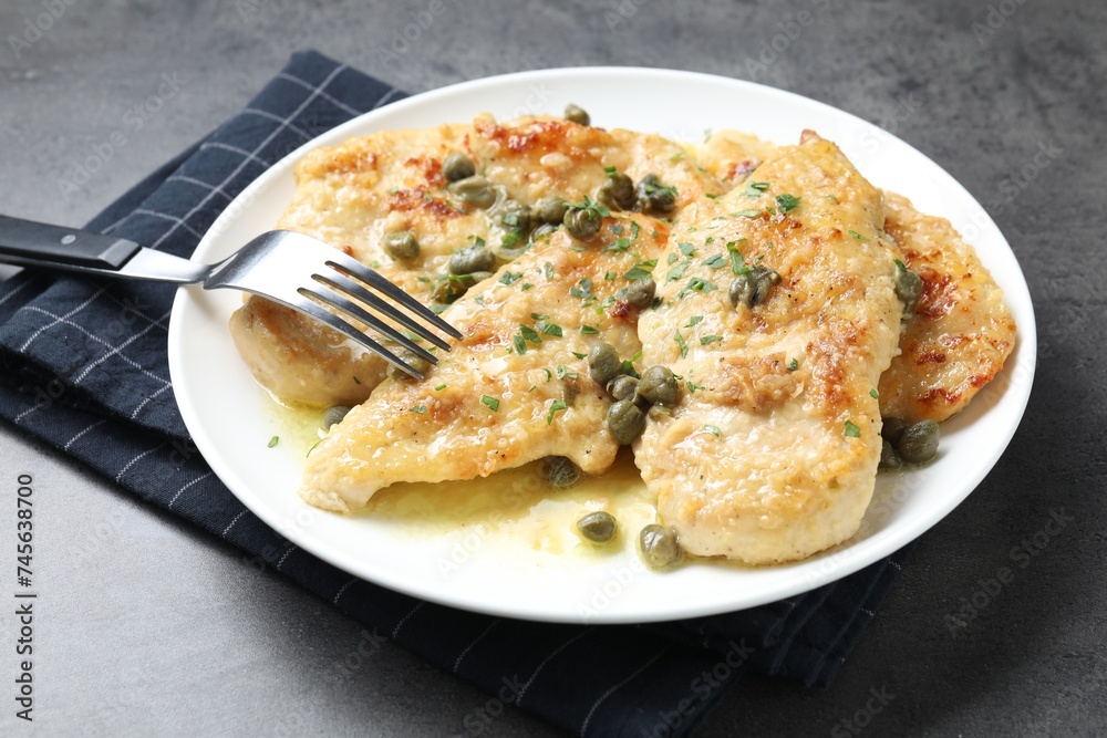 Delicious chicken piccata with herbs served on grey table