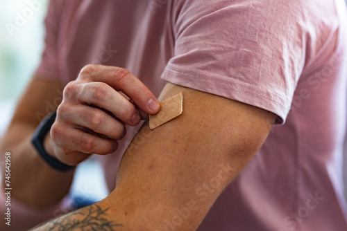 Young man putting nicotine patch on his shoulder, New Year's resolutions, quitting smoking, healthy lifestyle without cigarettes.